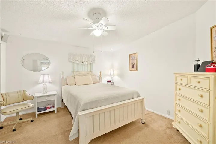 Bedroom with baseboards, light colored carpet, a textured ceiling, and a ceiling fan