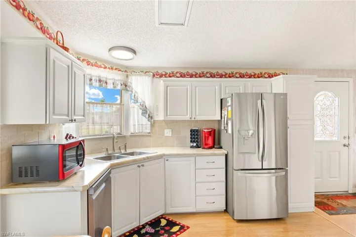 Kitchen with white cabinets, a sink, light countertops, light wood finished floors, and stainless steel appliances