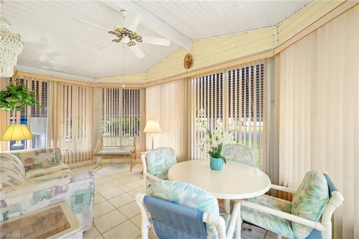 Sunroom with tile patterned floors and vaulted ceiling with beams