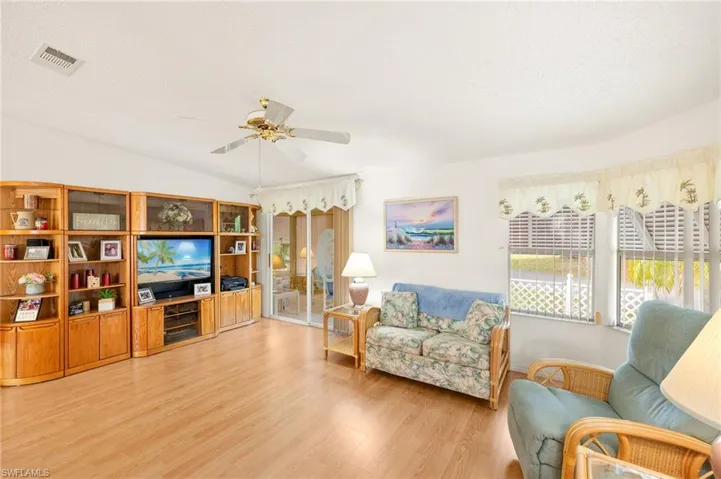 Living room featuring visible vents, a ceiling fan, light wood-style floors, a textured ceiling, and vaulted ceiling