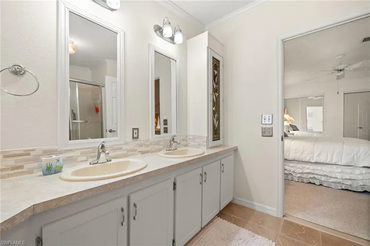 Bathroom featuring a sink, decorative backsplash, connected bathroom, and crown molding