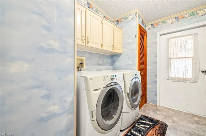 Washroom with a textured ceiling, washing machine and clothes dryer, and cabinet space