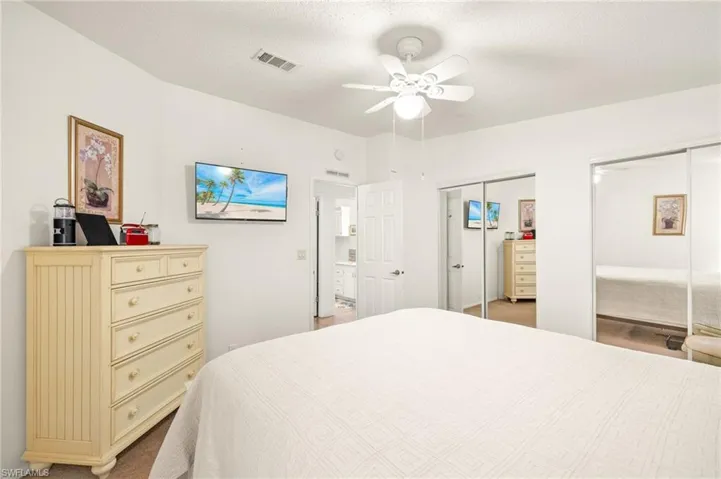 Bedroom featuring visible vents, a textured ceiling, multiple closets, and a ceiling fan