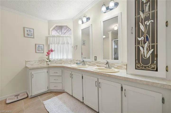 Bathroom featuring a textured ceiling, decorative backsplash, a sink, and visible vents
