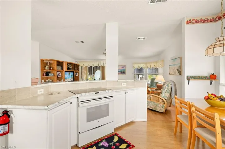 Kitchen featuring open floor plan, light wood finished floors, white cabinets, and electric stove