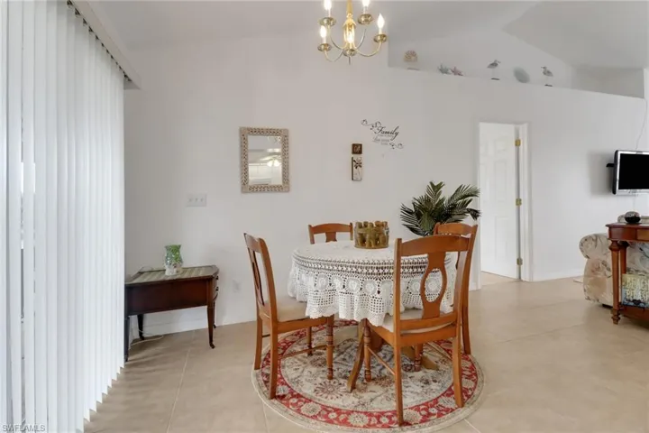 Dining space with lofted ceiling, light tile patterned floors, and a chandelier