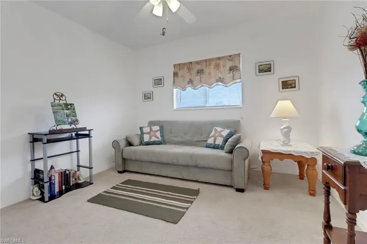 Carpeted living area with baseboards and a ceiling fan