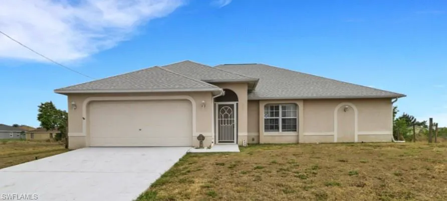 Single story home featuring driveway, stucco siding, an attached garage, and a front yard