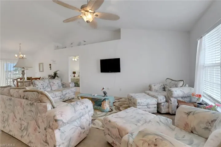 Living room with lofted ceiling and ceiling fan with notable chandelier