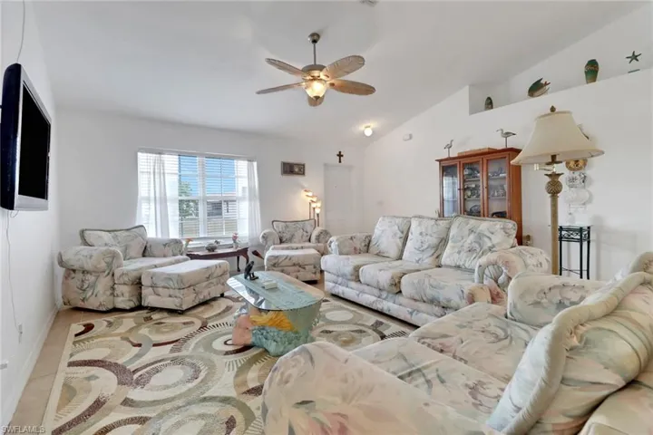 Living area with ceiling fan, vaulted ceiling, and tile patterned floors