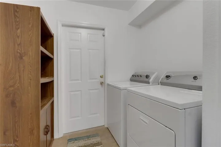 Washroom with laundry area, washer and clothes dryer, and light tile patterned floors