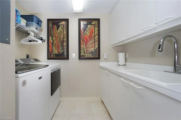 Laundry area featuring cabinets, sink, washing machine and dryer, and light tile patterned floors