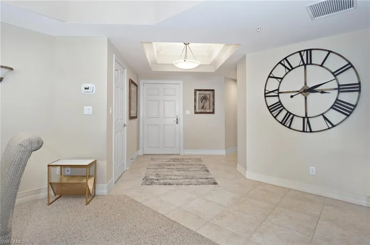 Entryway with ornamental molding, a tray ceiling, a skylight, and light tile patterned floors
