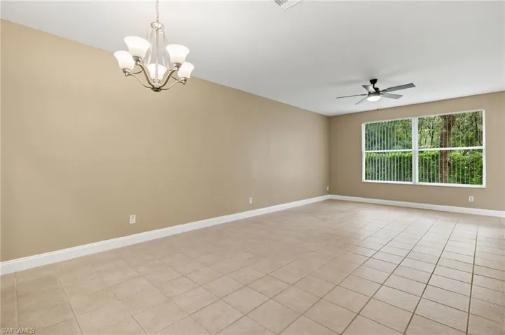 Open floor plan Living area with ceiling fan with notable chandelier and light tile patterned floors