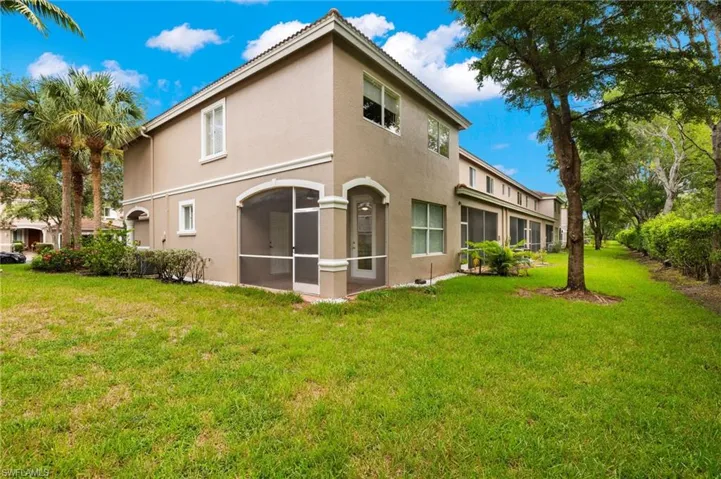 Back of property with a lawn and a sunroom