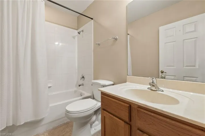 Full bathroom with tile patterned floors, vanity, shower / bath combination with curtain, and toilet