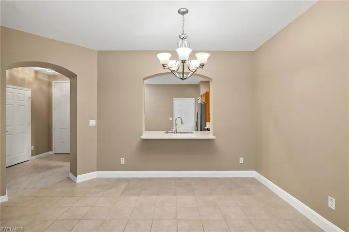 Open dining area with view of kitchen sink, a chandelier, and light tile patterned floors