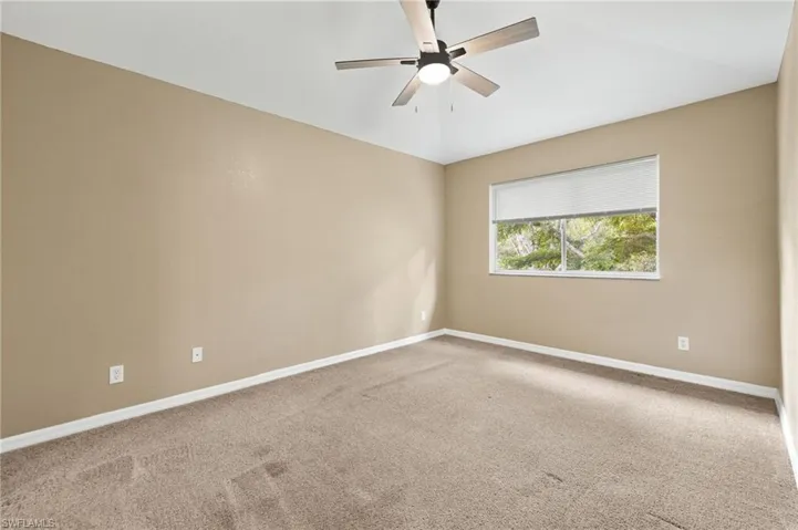 Carpeted spare room with ceiling fan and lofted ceiling