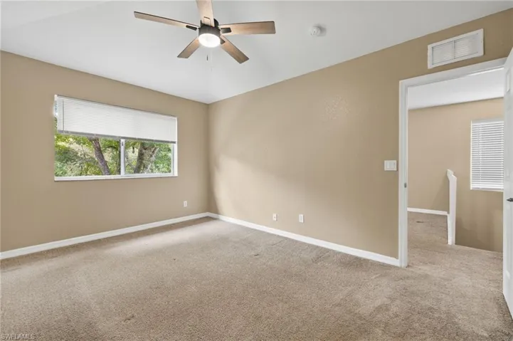 Unfurnished room featuring ceiling fan, light colored carpet, and lofted ceiling