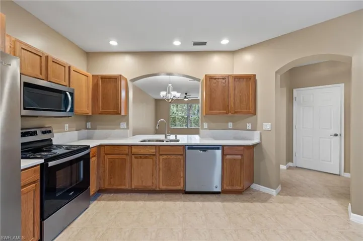 Kitchen with appliances with stainless steel finishes, a notable chandelier, light tile patterned floors, and sink