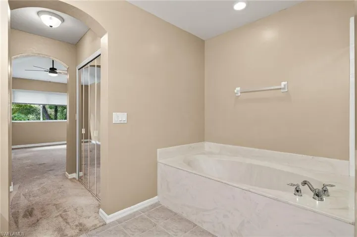 Bathroom featuring ceiling fan, a tub, and tile patterned flooring