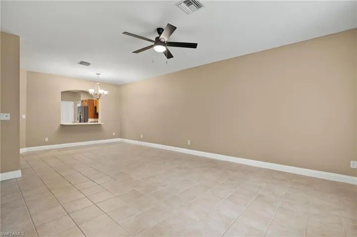 open concept!! with ceiling fan with notable chandelier and light tile patterned flooring