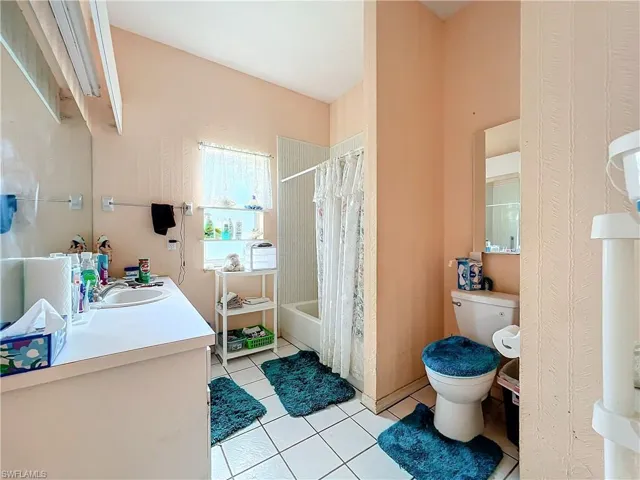 Full bathroom featuring tile patterned floors, toilet, vanity, and shower / bath combo with shower curtain