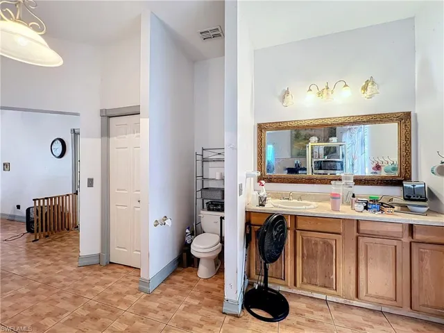 Bathroom with visible vents, baseboards, toilet, vanity, and tile patterned flooring