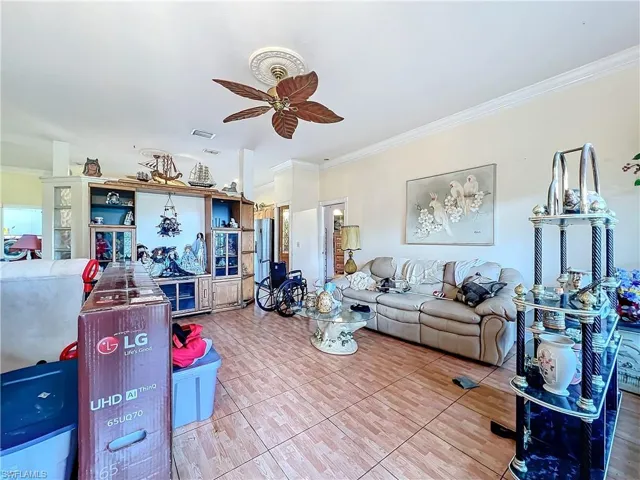 Living room featuring visible vents, crown molding, tile patterned floors, and a ceiling fan