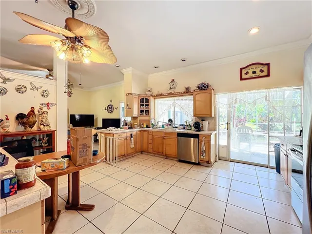 Kitchen with light countertops, ornamental molding, stainless steel dishwasher, light tile patterned flooring, and ceiling fan