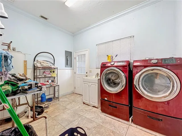 Laundry area with cabinet space, crown molding, electric panel, and washer and clothes dryer