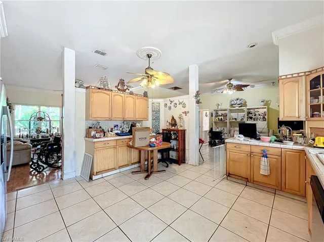Kitchen with crown molding, light tile patterned floors, visible vents, and a ceiling fan