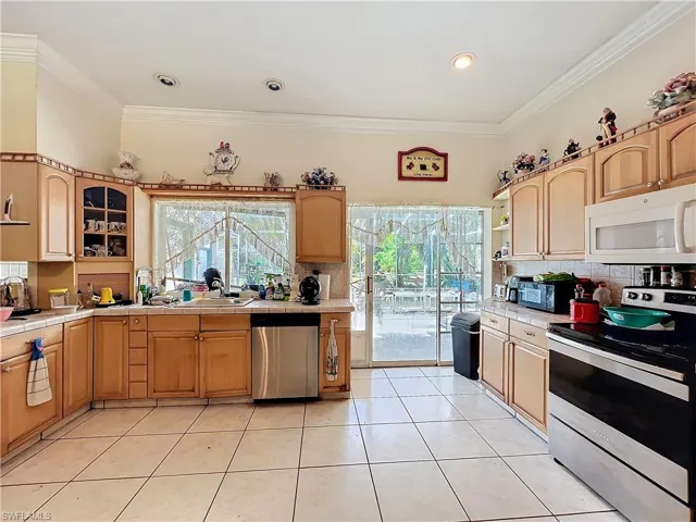Kitchen featuring ornamental molding, stainless steel appliances, and tile countertops