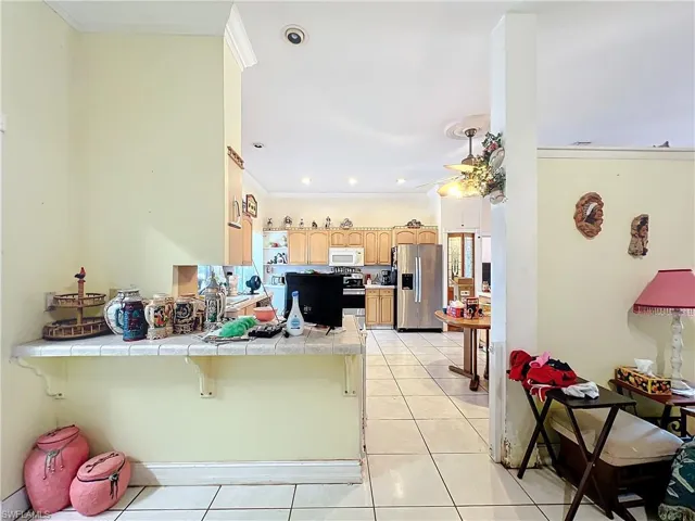 Kitchen featuring light tile patterned floors, stainless steel appliances, light brown cabinetry, tile countertops, and a peninsula