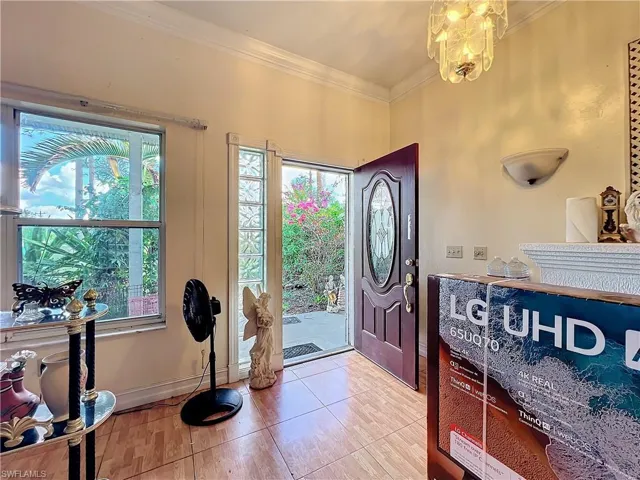 Entrance foyer with baseboards, a notable chandelier, and crown molding