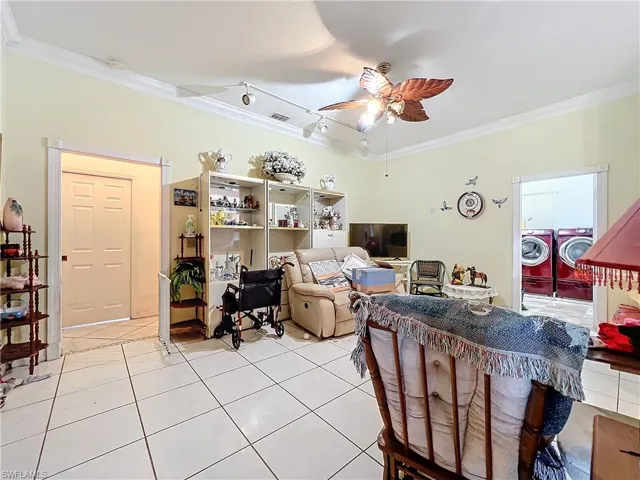 Living area featuring crown molding, washer and dryer, ceiling fan, and light tile patterned floors