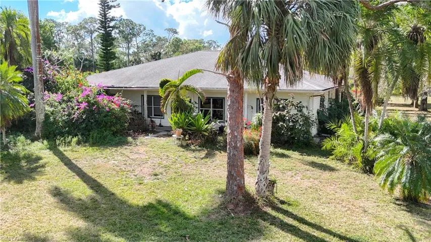 View of property hidden behind natural elements featuring a front lawn