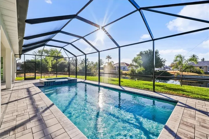 View of pool with a sunroom, glass enclosure, a pool with connected hot tub, a patio, and a yard