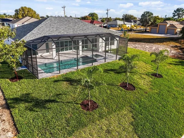 Outdoor pool with glass enclosure, a sunroom, a patio area, and a lawn