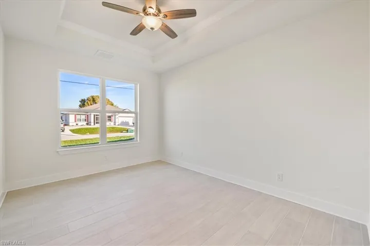 Unfurnished room featuring light wood-style flooring, a tray ceiling, crown molding, and ceiling fan
