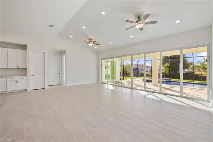 Unfurnished living room featuring vaulted ceiling, a ceiling fan, wood finish floors, and recessed lighting