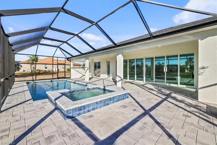 View of swimming pool featuring a sunroom, a patio area, a pool with connected hot tub, and glass enclosure