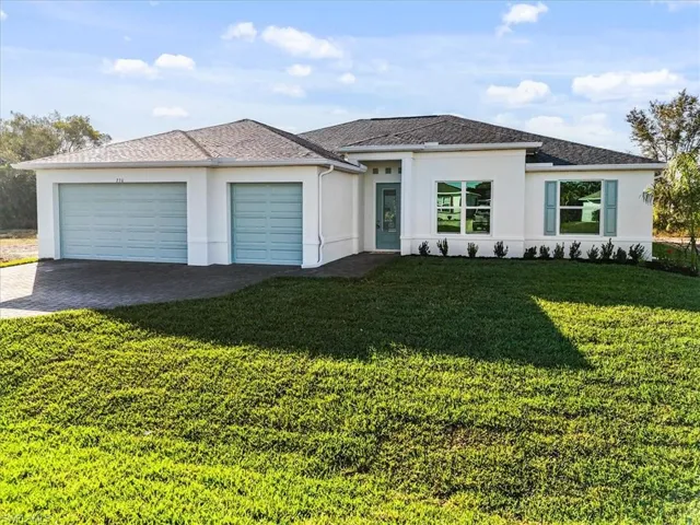 View of front of home featuring stucco siding, decorative driveway, an attached garage, and a front yard