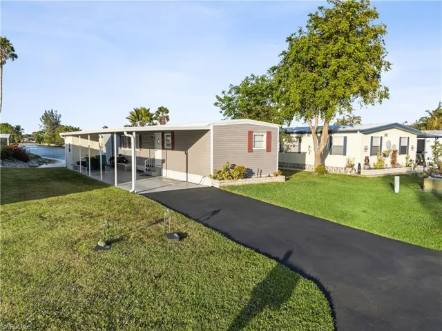 View of front of property with a front lawn, a carport, and driveway