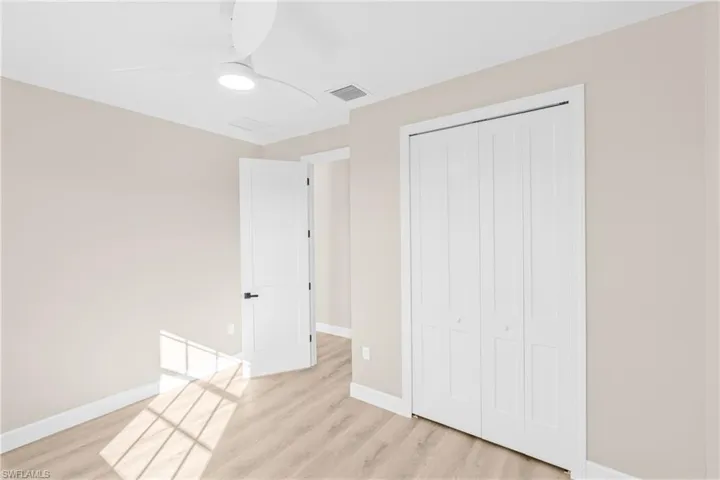Unfurnished bedroom with ceiling fan, a closet, and light wood-style floors