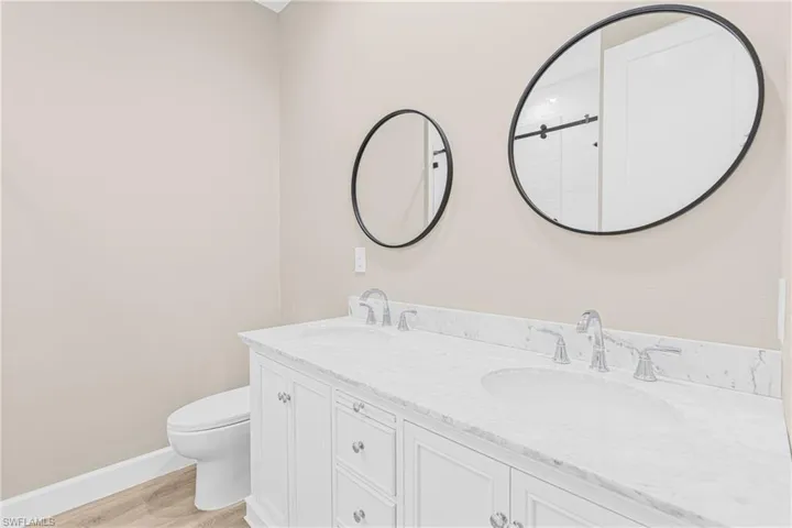 Bathroom featuring light wood-style floors, double vanity, and a shower with shower door
