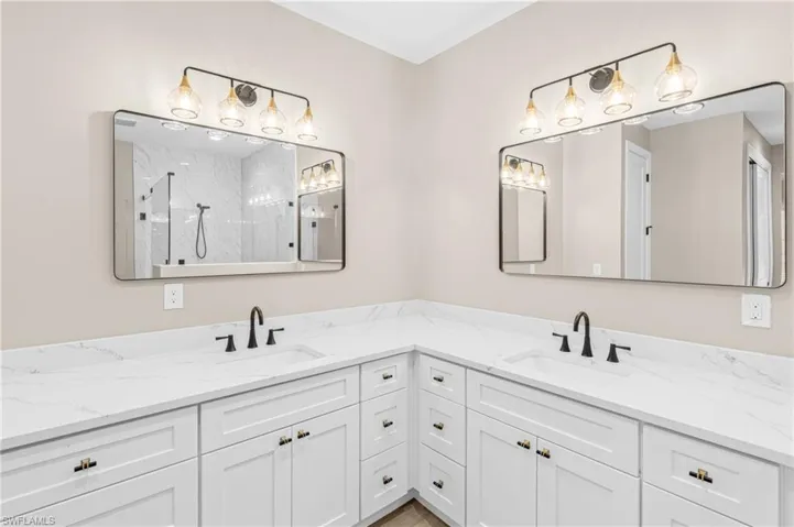 Full bathroom featuring a marble finish shower and double vanity