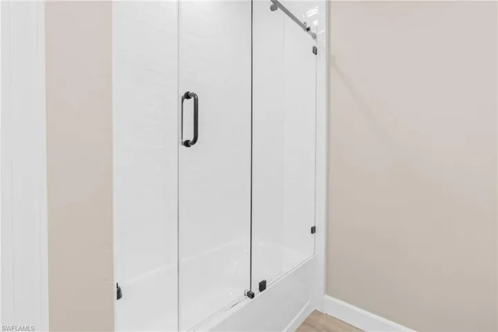 Bathroom featuring bath / shower combo with glass door and baseboards
