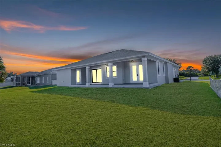 Rear view of property featuring a yard, stucco siding, and a patio