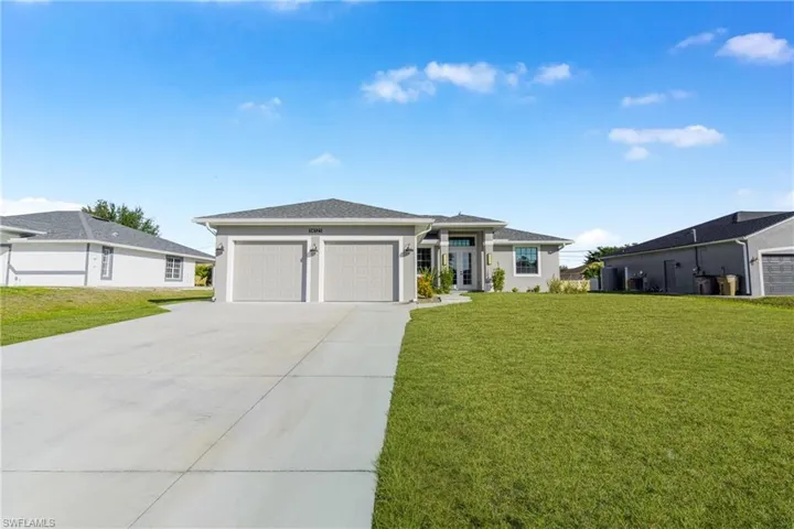 Prairie-style home featuring a front lawn, driveway, a garage, and stucco siding